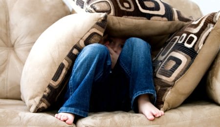 criança escondida atrás de almofadas no sofá - fobia