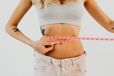 mulher com bulimia nervosa medindo sua barriga com fita métrica