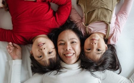 mãe e duas filhas meninas crianças deitadas na cama causas de autismo