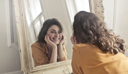 mulher se olhando no espelho e sorrindo