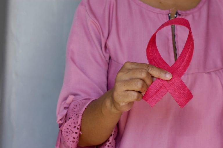 Mulher segurando laço outubro rosa- câncer de mama