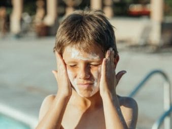 menino passando protetor solar no rosto