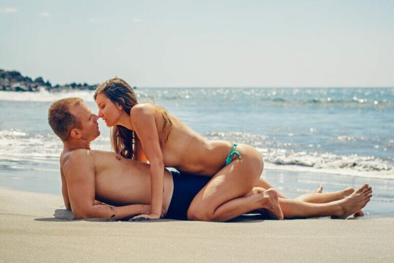casal com vício em sexo se beijando na praia com a mulher em cima do homem