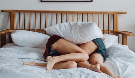 casal com vício em sexo deitados na cama com um travesseiro sob eles