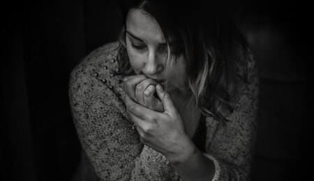 mulher em preto e branco roendo as unhas com transtorno de humor ansioso