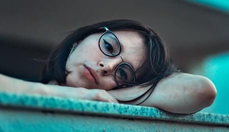 garota triste deitada na mureta com olhar triste