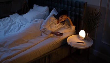 garota com depressão endógena deitada na cama usando o celular de noite