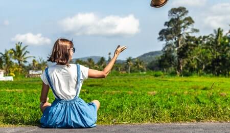 mulher no campo jogando seu chapéu de palha ao vento