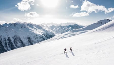 duas pessoas escalando uma montanha no inverno