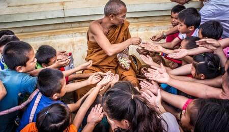 monge dando refeição para várias crianças praticando o altruísmo