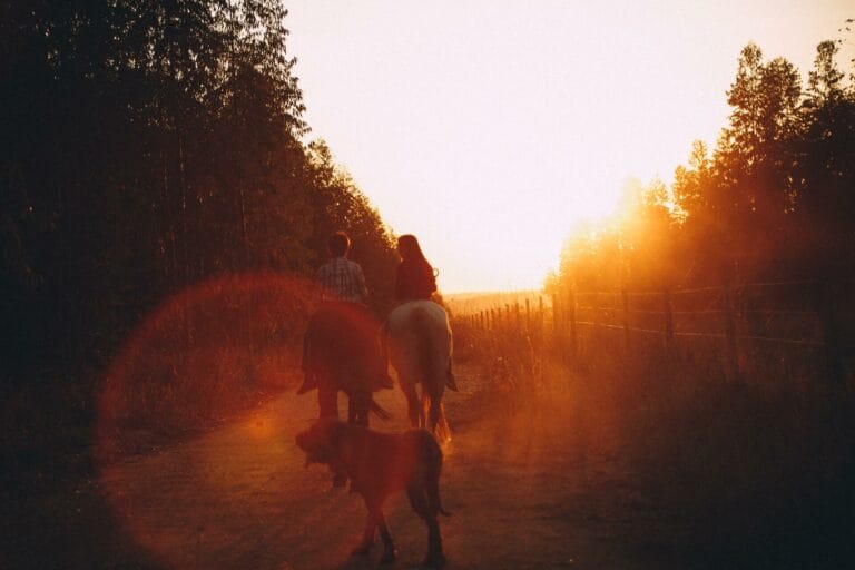 duas pessoas andando a cavalo praticando a equoterapia