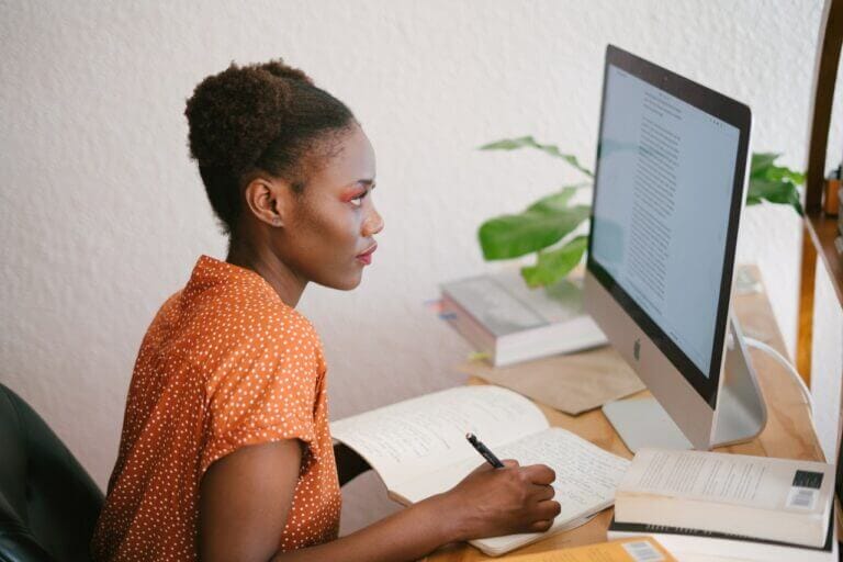 mulher olhando para o computador e anotando no caderno em diferentes tipos de aprendizagem