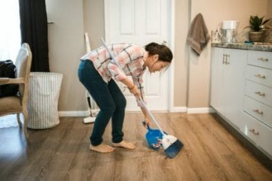 mulher varrendo o chão da casa