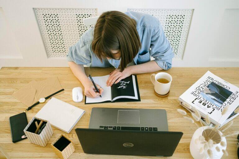 mulher escrevendo sentada na frente do computador depois de fazer a terapia de aceitação e compromisso