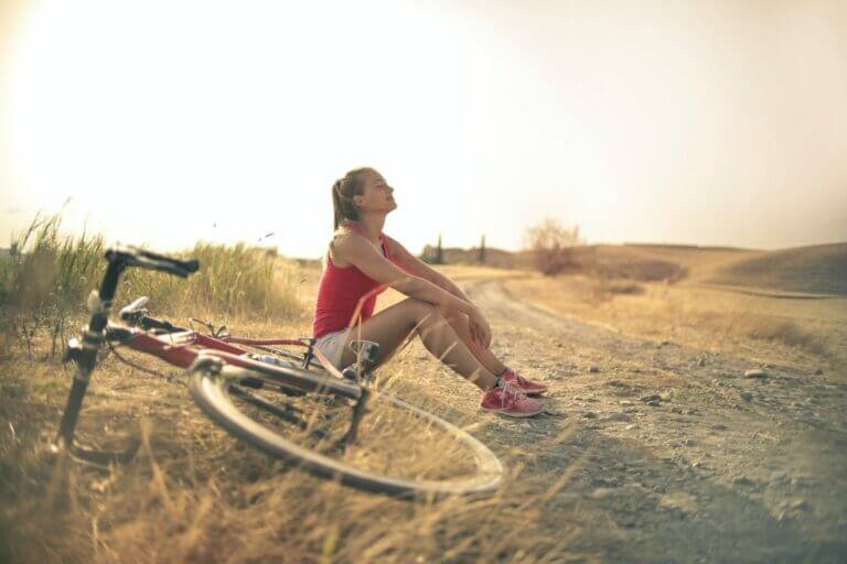 mulher sentada ao lado da bicicleta após pedalar é uma ótima idea de como manter a calma em dias difíceis