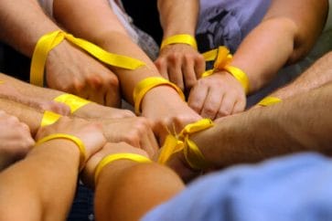 mãos unidas por uma fita amarela simbolizando como ajudar no setembro amarelo 2022