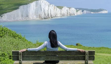 mulher sentada olhando para o mar para aliviar o estresse