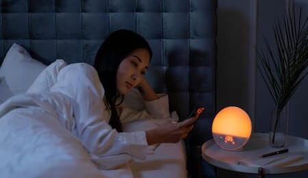 exemplo de cronotipo vespertino com uma mulher deitada na cama usando o celular as 1 da manhã