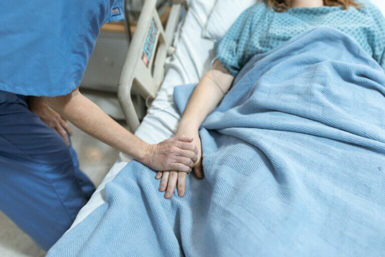 homem segurando a mão de uma mulher no hospital em coma