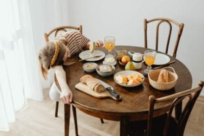 adolescente cansada dormindo na mesa do café da manhã mostrando a importância de começar a aula mais tarde