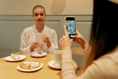 mulher tirando foto de amiga com cabelo raspado por causa do câncer de mama