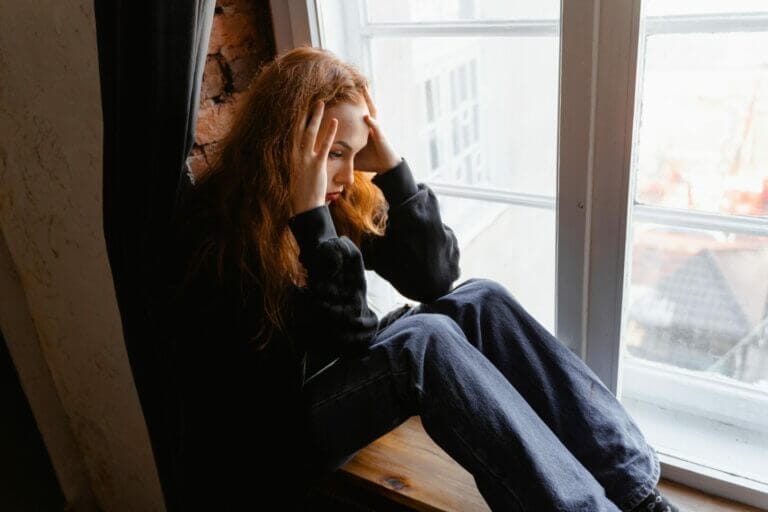 mulher sentada na janela triste por causa do pensamento intrusivo