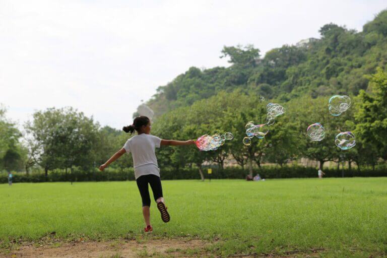 criança com bolhas de sabão fazendo brincadeiras ao ar livre