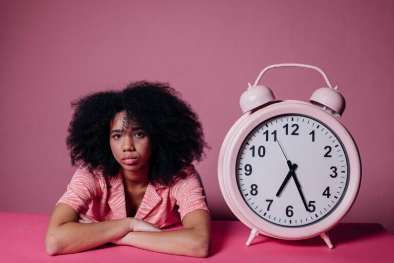 menina ao lado de relógio rosa mostrando o teste de cronotipo do sono