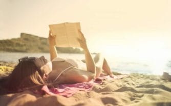 Garota lendo livros na praia durante férias