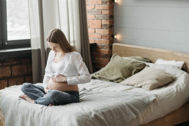 mulher grávida com depressão perinatal sentada na cama