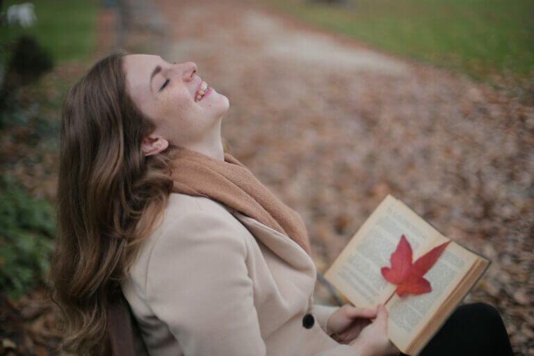 mulher feliz lendo um livro depois de aprender a como praticar o autoperdão