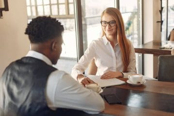 homem e mulher sentados na mesa para entrevista de emprego